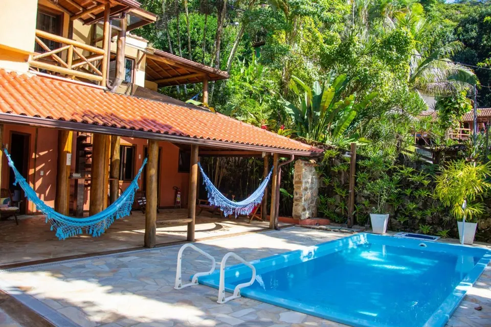 Piscina da Pousada Casa Bonita com varanda coberta, redes azuis e jardim tropical - pousada em Ilha Grande