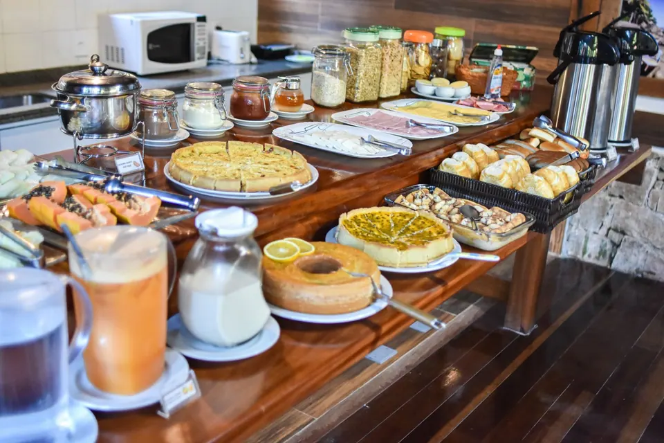 Bufê de café da manhã com bolos, pães, frios, frutas e sucos da Pousada Mata Nativa, Ilha Grande