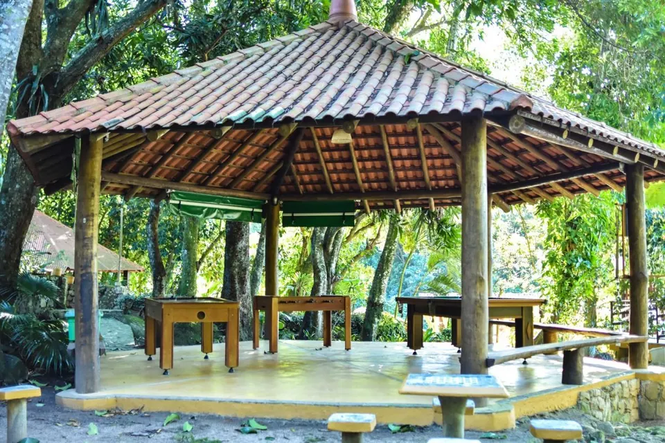 Salão de jogos com pebolim em quiosque cercado de árvores na Pousada Mata Nativa